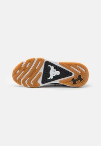 Suola della scarpa con battistrada arancione e bianco, sezione triangolare nera con logo di testa di toro e logo Under Armour nell'area del tallone.