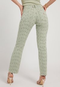 Pantaloni ricamati verde chiaro con design a gamba dritta, caratterizzati da motivi floreali, tasche posteriori standard e vita con cinturino.
