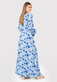 Blå blomster maxi kjole med lange ærmer, der har en tætsiddende talje og en svævende nederdel, lavet af letvægtsstof med en glat tekstur.