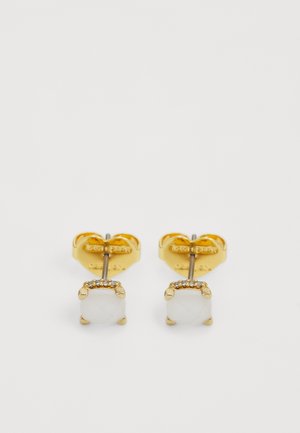Guldfärgade studs med en kvadratisk vit sten med en strukturerad yta, accentuerad av en rad små klara stenar längs toppen.