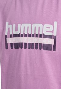 Lys lilla bomulds t-shirt med "hummel" logo i fede hvide bogstaver og "SPORTSWEAR" i lys pink; har et geometrisk mønster design.