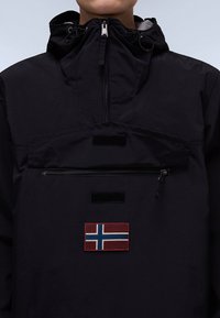 Giacca anorak nera con zip a un quarto, cappuccio regolabile, tasca sul petto con zip e una toppa della bandiera norvegese.