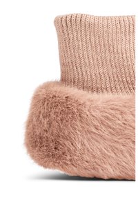 Stickad rosa strumpa med en fluffig fuskpäls-kant. Fuskpälsen har en mjuk, voluminös textur. Den ribbade mönstringen ger visuell intresse till designen.