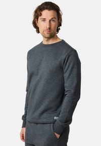 Gray crewneck sweatshirt made from soft fabric. Features ribbed cuffs and hem, with a subtle logo tag at the bottom. Minimalist design.