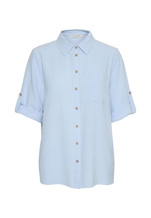 Camicia azzurra chiaro con colletto classico, maniche arrotolate, taschino sul petto e bottoni marroni sul davanti. Tessuto dalla texture liscia.