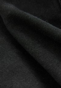 Melnas auduma ar mīkstu, struktūrētu virsmu. Materiāls izskatās austs un tam ir smalka spīduma, kas parāda salocītas kārtas un dziļumu.