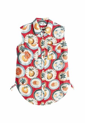 Chemise rouge sans manches avec un motif de fruits comprenant des oranges, des ananas et des citrons sur un fond bleu clair imitant une assiette. Fermeture boutonnée à l'avant et liens sur les côtés.