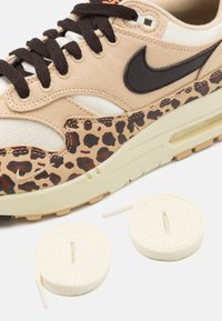 Beige kedu ar leopardu rakstu akcentiem, teksturēts audums augšdaļā, tumši brūns logo un krēmkrāsas šņorītes. Iekļautas divas papildu krēmkrāsas šņorītes.