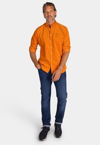 Oranje blouse met lange mouwen en een borstzak, gecombineerd met donkerblauwe spijkerbroek. Casual pasvorm, opgerolde mouwen en een gestructureerde stof.