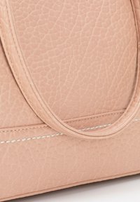 Roze leren handtas met een gestructureerde afwerking, voorzien van gladde hengsels en witte stiksels. Het ontwerp bevat subtiele lijnen en een gestructureerde vorm.