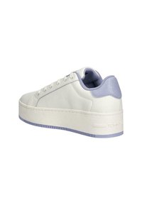 Witte sneaker met een plateauzool, voorzien van een gladde afwerking, licht paarse accenten en ronde veters. Getextureerd hielgedeelte aan de achterkant.