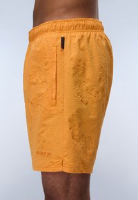 Pantalones cortos naranjas con textura y un patrón floral, cinturilla elástica, bolsillo lateral y un pequeño logo en el dobladillo.