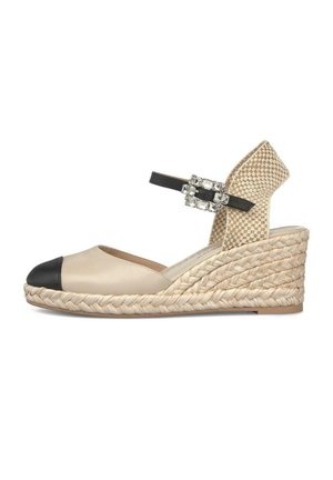 Alpargata cuña beige con puntera negra, tira de talón tejida y tira de tobillo negra con una hebilla decorativa de pedrería.