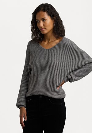 Grau, gerippter Strickpullover mit V-Ausschnitt und lockerer Passform. Die langen Ärmel haben geraffte Bündchen und werden mit schwarzen Hosen kombiniert.