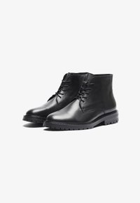 Botas negras de cuero hasta el tobillo con un acabado suave, que cuentan con una punta redondeada, cierre de cordones y una suela de goma texturizada para mayor tracción.