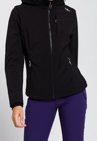 Czarna kurtka softshell z kapturem, z zamkiem z przodu i kieszeniami, wykonana z elastycznego materiału o dopasowanym kroju.