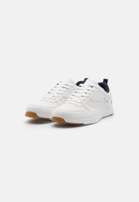 White athletic shoes with a smooth leather upper, navy accents on the heel, perforated detailing, and a gum rubber sole.