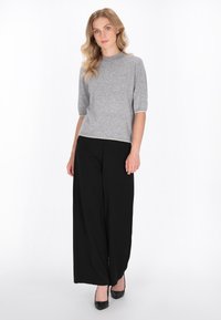 Un top gri cu mânecă scurtă, cu decolteu rotund și un buzunar pe piept, asortat cu pantaloni negri cu croială largă și pantofi cu toc negri. Design curat, accente minime.