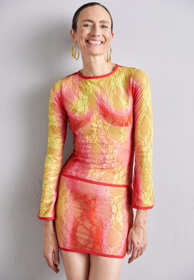 Long-sleeve mesh top and mini skirt in a gradient of pink, yellow, and orange with a lace pattern, featuring red trim and accents.