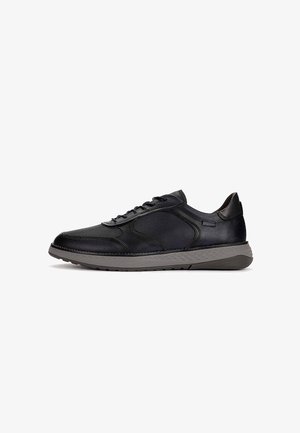 Zapatilla deportiva negra de corte bajo con empeine mixto de cuero y malla, suela gris texturizada y cierre de cordones sobre fondo blanco.