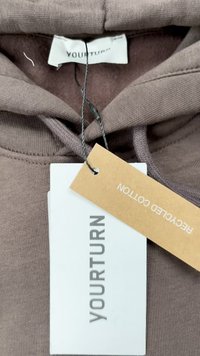 Sudadera marrón de algodón reciclado con un acabado texturizado, que presenta cordones y etiquetas que muestran "YOURTURN" y "COTTON RECICLADO."