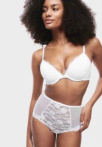 Weißer Spitzen-BH mit geschwungenen Kanten und verstellbaren Trägern, kombiniert mit hoch taillierten, transparenten Mesh-Slips mit Spitzen-Einsätzen.