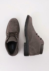 Botas de tobillo de ante gris con puntera redonda, diseño de cordones, suela de goma negra en contraste y detalles de costura en la parte superior.