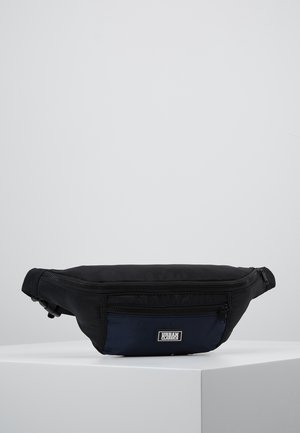 Czarna i granatowa nerka z dwoma zamykanymi na zamek komorami oraz etykietą „Urban Classics” na przedniej kieszeni, prezentowana na białej powierzchni.