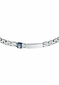 Silverfärgad metallarmband med rektangulära länkar. Har en marinblå accent och en logotyp i mitten. Slät, polerad yta.
