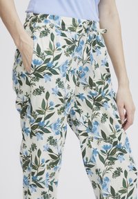 Blomsterbyxor i lätt tyg med ett blått och grönt botaniskt tryck, elastisk midja, dragsko och sidofickor.
