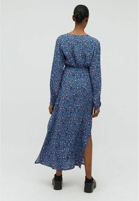 Robe maxi à manches longues, bleue, à fleurs, avec une taille cintrée, une fente sur le côté et en tissu léger, ornée de motifs de fleurs roses et violettes.