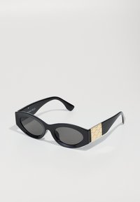 Black sunglasses with oval lenses, a sleek frame, and a textured gold accent on the sides. The design features smooth curves and a glossy finish.