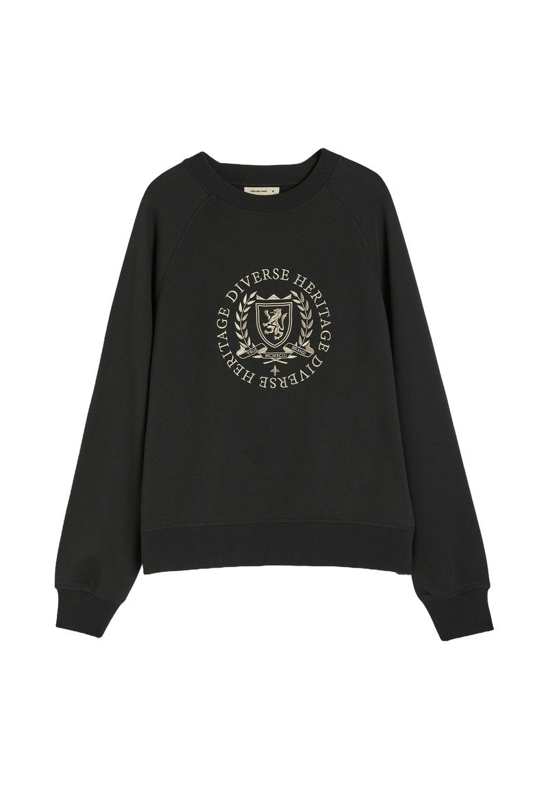 Czarny sweter z rękawami raglanowymi, z okrągłym złotym emblematem na przodzie, na którym widnieje napis "Różnorodne Dziedzictwo" w otoczeniu laurowego ornamentu.