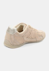 Baskets en suède beige avec une surface texturée, des lacets et une accentuation scintillante au talon. Elles disposent d'une semelle en caoutchouc flexible pour le confort et la traction.