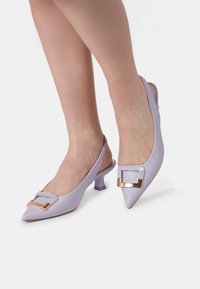 Svetlo violetni usnjeni slingback petkoti s koničastim nosom, zlatim pravokotnim sponkam in nizko blokasto peto. Gladka tekstura, eleganten dizajn.