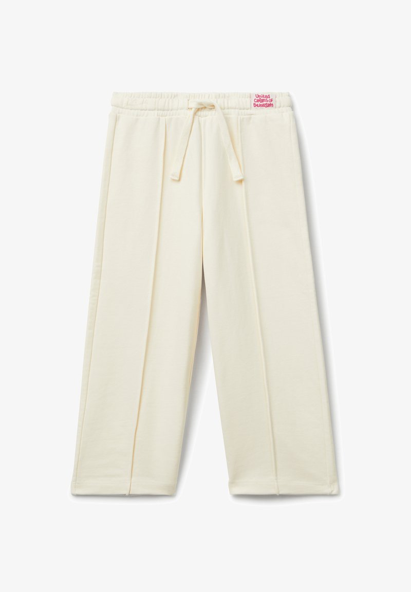 Krémové kalhoty s širokými nohavicemi, elastickým pasem a stahovací šňůrkou, se svislými švy a malou červenou nášivkou na pase.