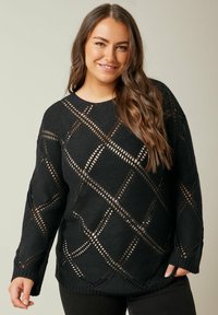 Schwarzer Strickpullover mit offenem Rautenmuster, langen Ärmeln und rundem Ausschnitt. Die strukturierte Gestaltung erhöht das visuelle Interesse.