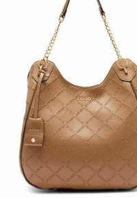 Sac à main en simili cuir marron avec motif matelassé en losanges, garnitures dorées et bandoulière à double chaîne. Présente un logo et une étiquette latérale.