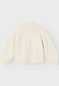 Pull crème en maille torsadée avec un col montant, coupe oversize, et des poignets et ourlet côtelés. Texture douce avec un motif en relief.