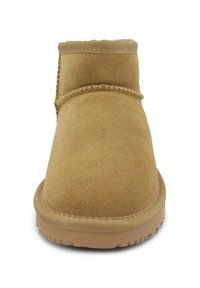 Stivale ankle in suede beige con punta arrotondata, caratterizzato da dettagli in cucitura e suola in gomma. Design semplice, texture morbida.