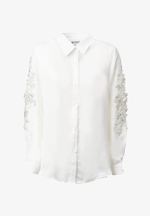 Hvid skjorte med lange ærmer, der har sølvfarvet blomsterbroderi og perleudsmykninger på ærmerne. Klassisk krave og strømlinet pasform.