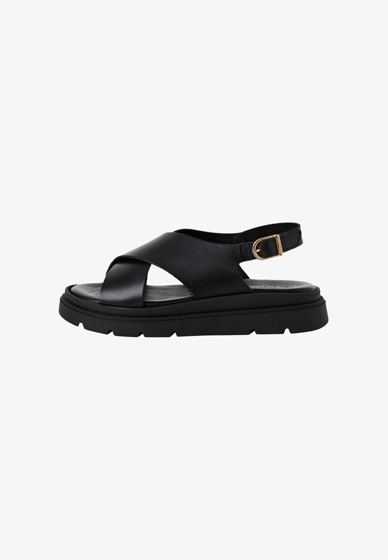 Sandale en cuir noir avec larges brides croisées, boucle de cheville réglable et semelle épaisse à crampons.