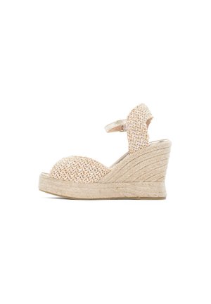 Beżowa pleciona sandałka na koturnie z paskiem wokół kostki i podeszwą na platformie owiniętą jutą, otwarty nosek, widok boczny na białym tle.