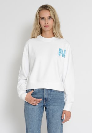 White cropped sweatshirt with a round neck, featuring a turquoise letter "N" design on the left chest. Material appears soft and textured.
