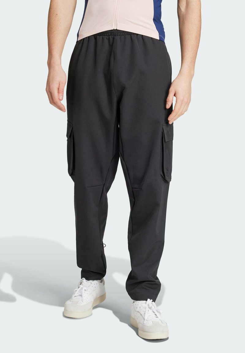Schwarze Cargo-Hosen mit elastischem Bund, seitlichen Taschen, entspannter Passform und einem glatten, leichten Stoff. Weiße Sneaker abgebildet.