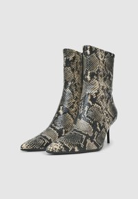 Stivaletti alla caviglia in pelle di serpente con punta affusolata, tacco sottile e tonalità terrose di nero e beige con una finitura testurizzata.