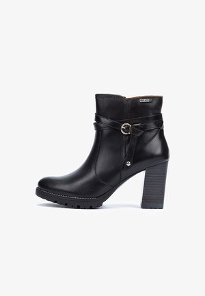 Botte de cheville en cuir noir avec un talon épais, détail de boucle sur le côté et semelle texturée. Présente une finition lisse et de subtils accents de couture.