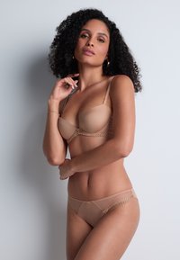 Ensemble de lingerie nu comprenant un soutien-gorge rembourré avec des accents en dentelle et des détails transparents, accompagné d'un slip assorti. Tissu doux et lisse.