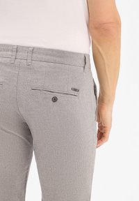 Grijze broek met patroon en slim fit, voorzien van achterzakken met knoopsluitingen en een gestructureerde stofafwerking.