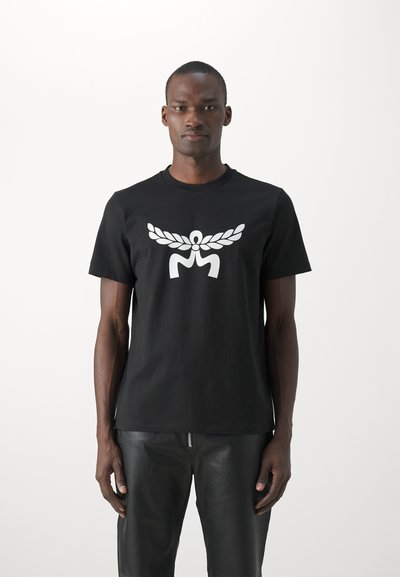 Czarny bawełniany t-shirt z dużym białym graficznym emblematem skrzydeł oraz centralną postacią. Fason jest standardowy, z okrągłym dekoltem.